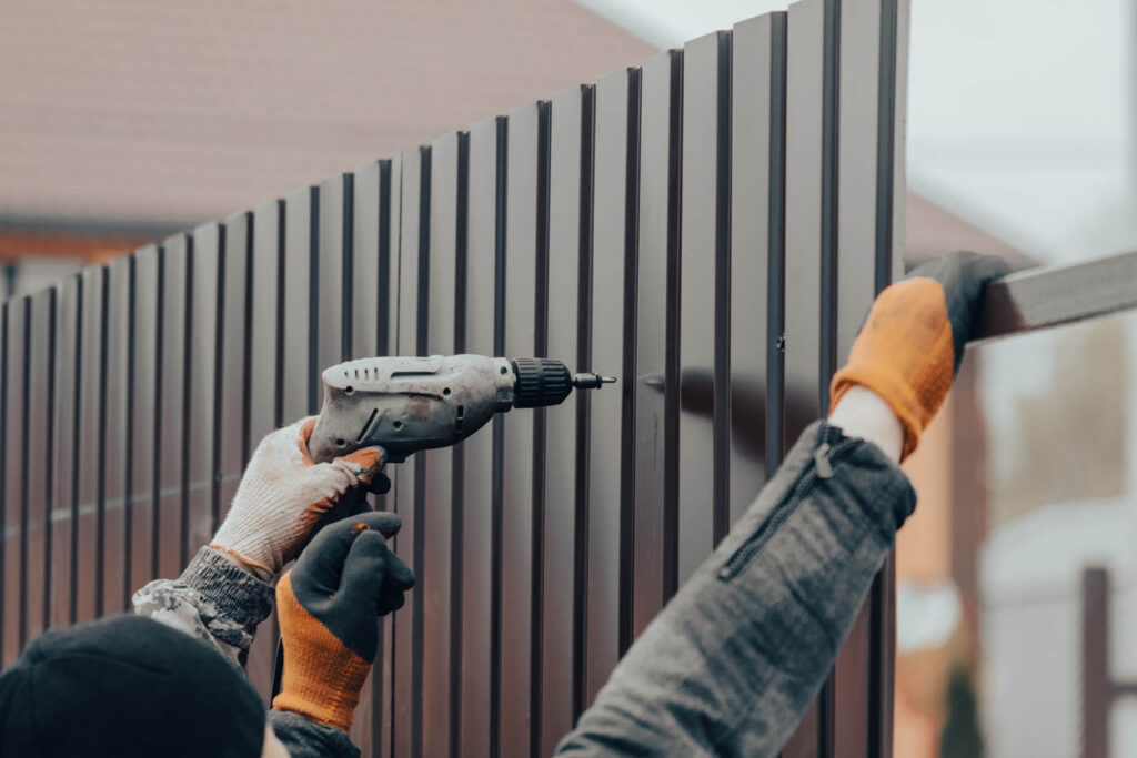 Workers install a metal profile fence.